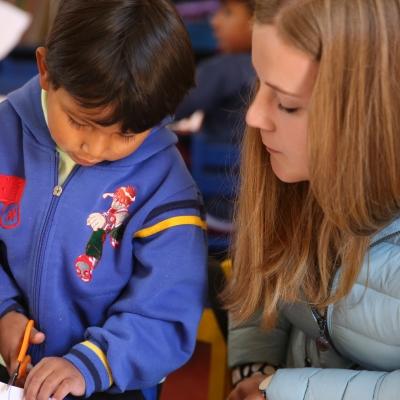 Een vrijwilliger tussen 18 en 25 jaar helpen een kind met een klasactiviteit tijdens haar vrijwilligerswerk kinderopvang in Peru. Als deel van de groepsreis kinderopvang in Peru, helpen Projects Abroad vrijwilligers tussen 18 en 25 in de klaslokalen.